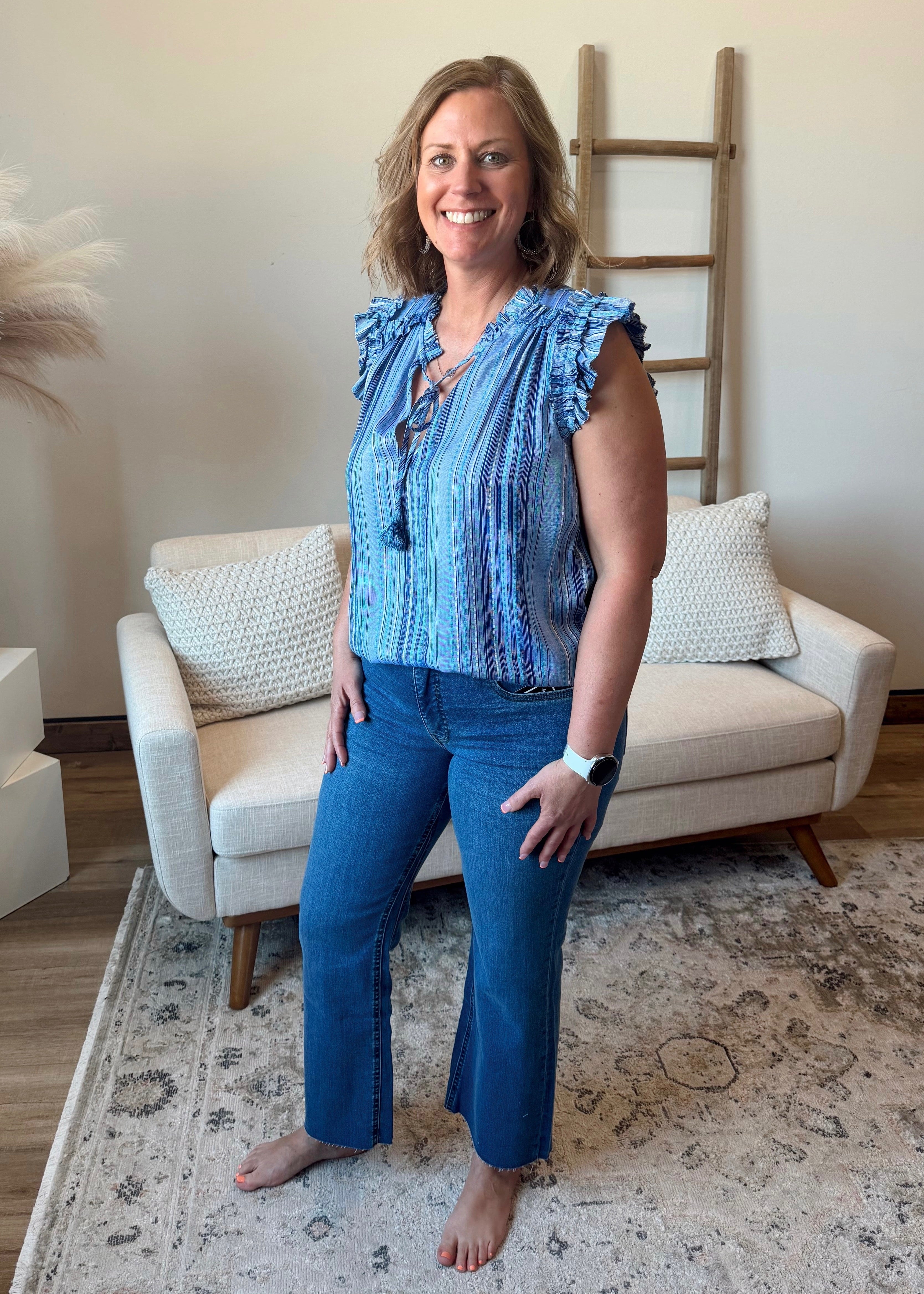 Woman in a blue striped top and jeans standing in a living room.
