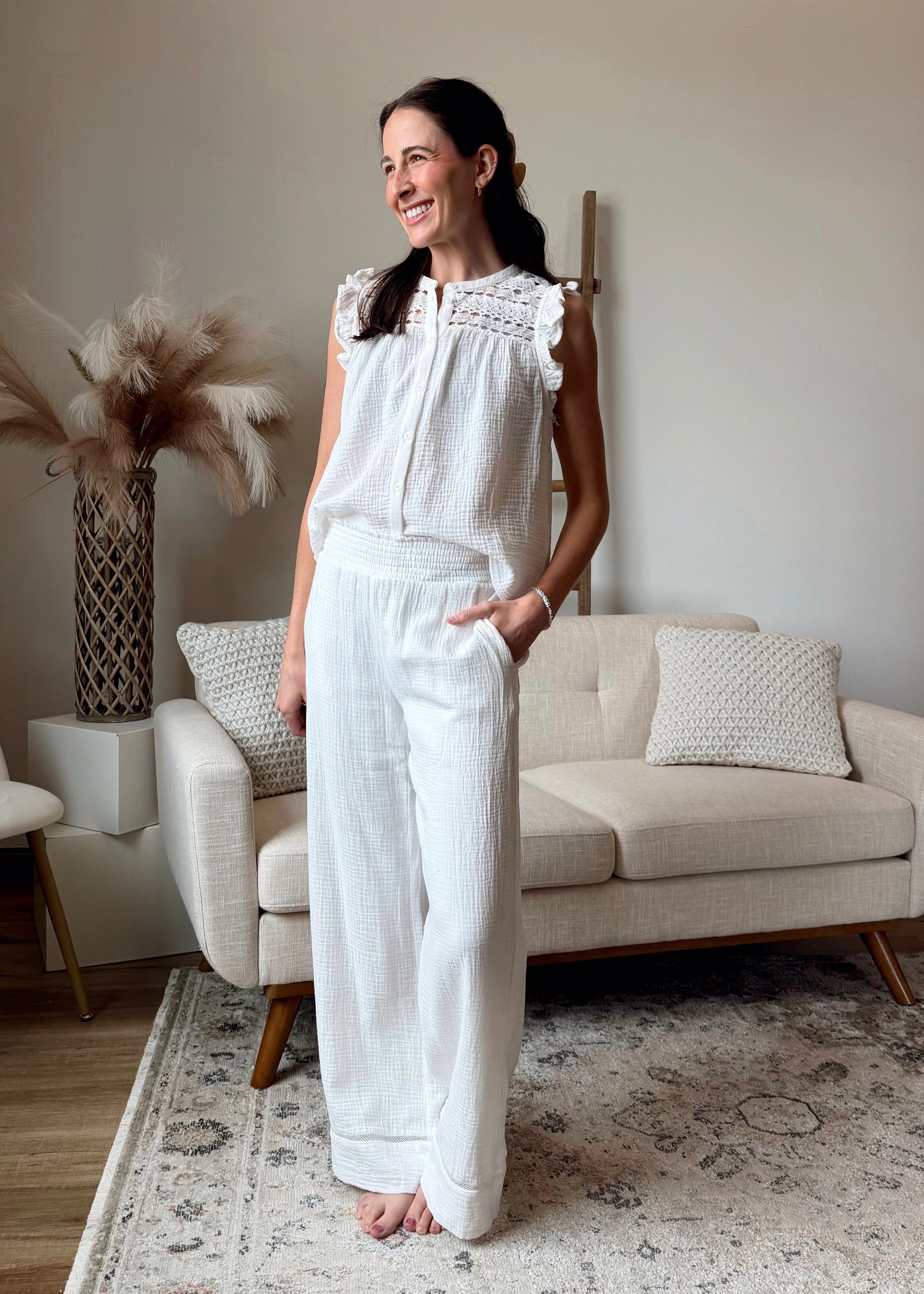 Woman in a white outfit standing in a living room with a neutral color scheme.